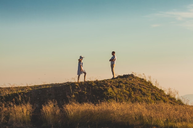 Distant photo of woman walking up the hill to meet her husband Woman making last efforts to solve the family conflict Man standing on the top of the hill with crossed hands feeling superiority