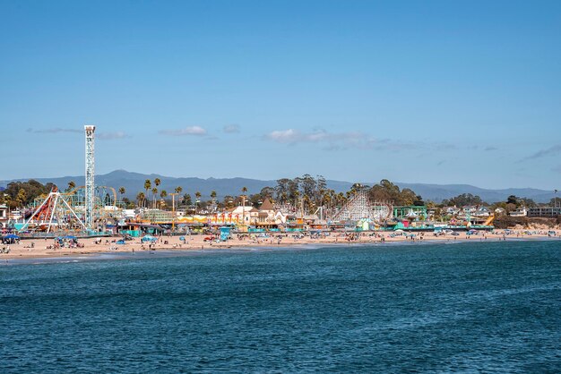 Photo distant view of amusement park rides and santa cruz beach in front of ocean