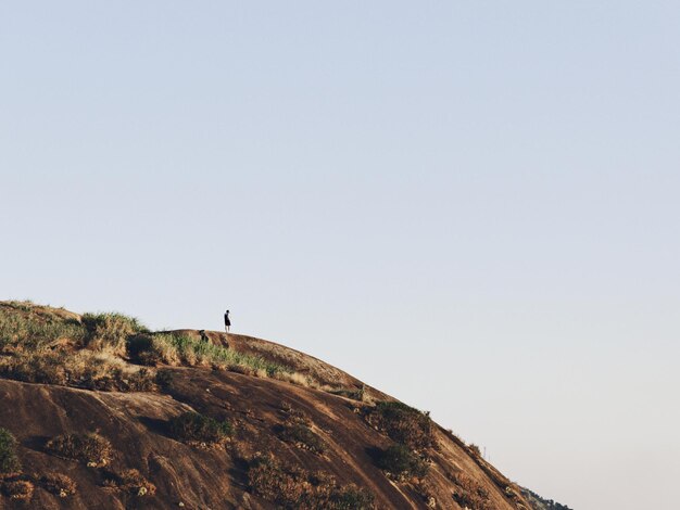 写真 明るい空を背景に山の上に立っている人の遠くの景色