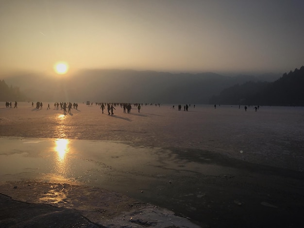 Distant view of people on frozen lake against sky