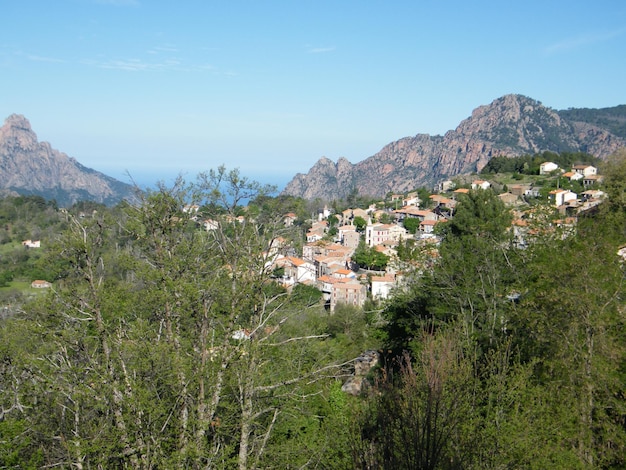 Distant view of town on mountain by forest against sky