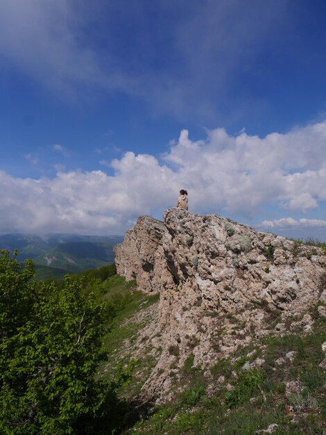 Foto donna lontana seduta in cima alla montagna