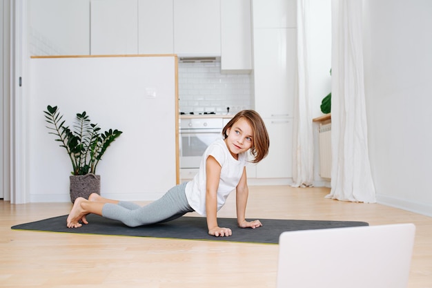 Distracted nine year old girl trying to do a plank on a mat at home