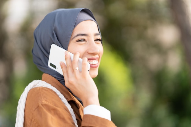 Distracted smiling muslim woman talking to the mobile