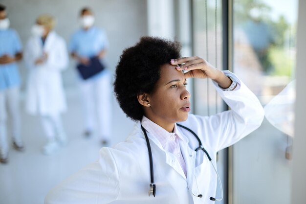 Distraught African American doctor looking through the window at medical clinic