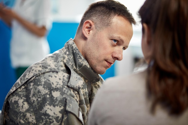 distraught army soldier communicating with his wife while waiting in a hallway at medical clinic