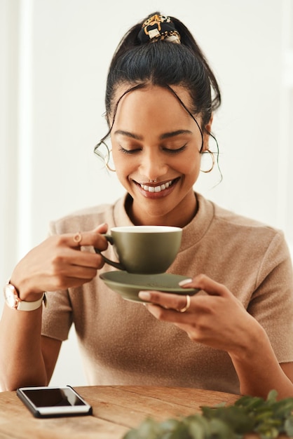 Dit goede humeur werd gesponsord door koffie Bijgesneden opname van een aantrekkelijke jonge vrouw die alleen in haar huis zit en geniet van een kopje koffie