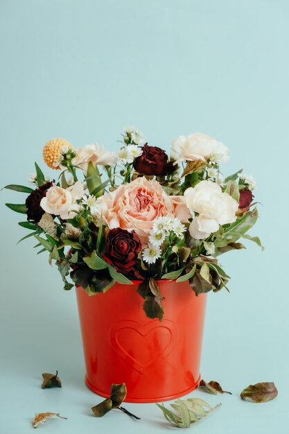 Dit is een boeket van verwelkende bloemen in een decoratieve emmer op een blauwe achtergrond Herfsttijd