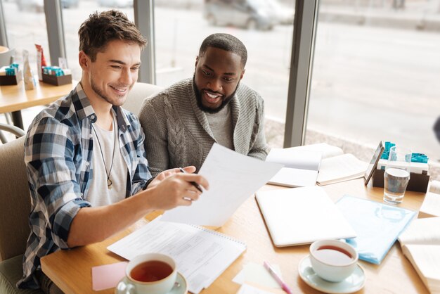 Dit is het antwoord. twee knappe internationale studenten lezen samen notities tijdens het studieproces in café.