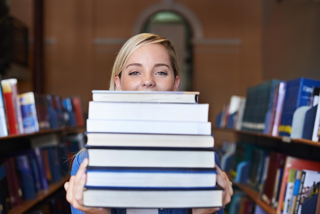 Dit is mijn studiemateriaal voor het semester Portret van een mooie jonge student die een grote stapel schoolboeken vasthoudt