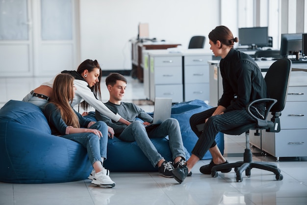 Dit kan interessante informatie zijn. Groep jonge mensen in vrijetijdskleding die in het moderne bureau werken