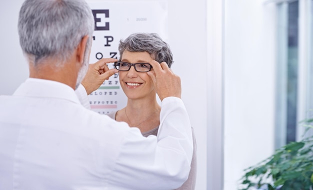 Dit paar is perfect voor jou Shot van een optometrist die een bril op een patiënt zet