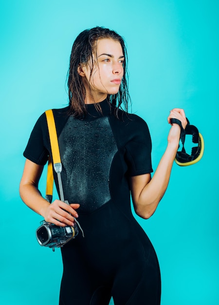 Dive deep. Sensual woman with scuba gear and dive equipment. Sexy diver with wet hair holding dive mask and camera for underwater shooting. We dive 360 days a year