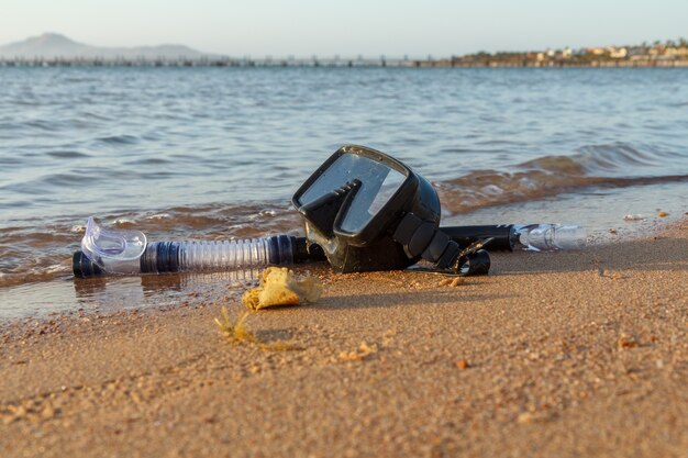 Dive mask and a snorkel for professionals on sand with a sea on the background. Travel and vacation concept.