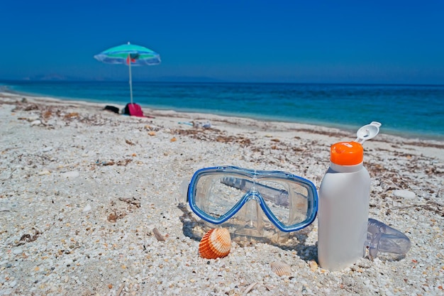 Maschera subacquea e crema solare in spiaggia