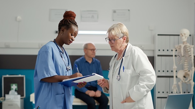 Divers medisch team dat controledocumenten op kantoor analyseert om een ziektediagnose te vinden en de patiënt te helpen met herstel. Overlegafspraak met onderzoeksresultaten voor het geven van een receptbehandeling.