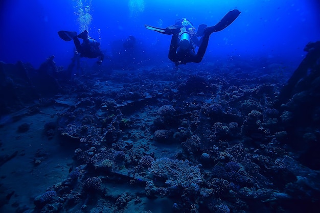 дайверы под водой на глубине на фоне синего моря