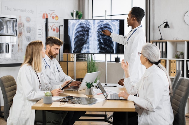 Diverse artsen controleren röntgenscan van longen op monitor
