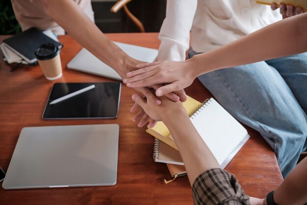 Foto diverse aziatische universiteitsstudenten zetten hun handen bij elkaar om elkaar aan te moedigen en te ondersteunen als een team vriendschapsconcept