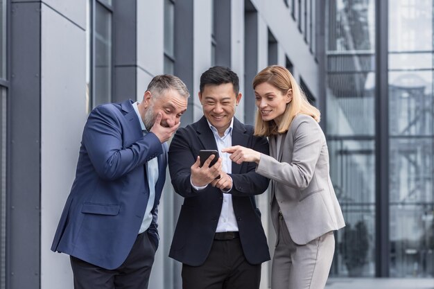 Gruppo di diverse imprese tre lavoratori maschi e femmine al di fuori dell'edificio per uffici sorridendo allegramente e