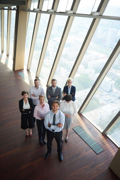 現代の明るいオフィスインテリアでチームとして一緒に立っている多様なビジネスの人々のグループ