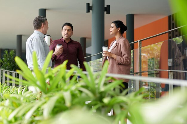 Diverse business team standing in office, drinking coffee and
discussing news