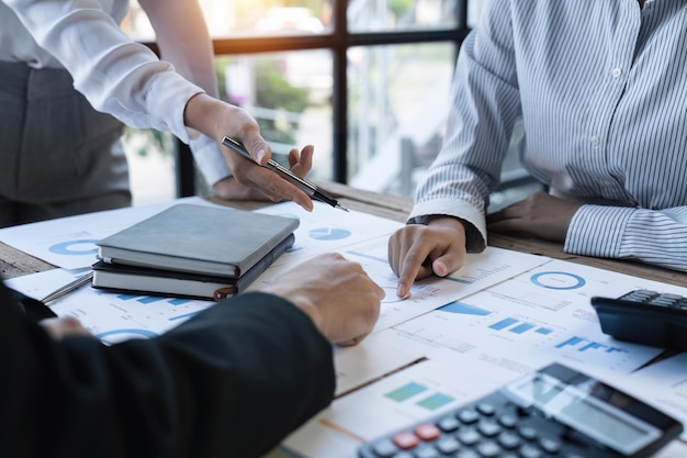 Photo diverse businesspeople cooperate work together discussing company financial statistics multiracial colleagues employees collaborate brainstorm with finance document at meeting close up shot