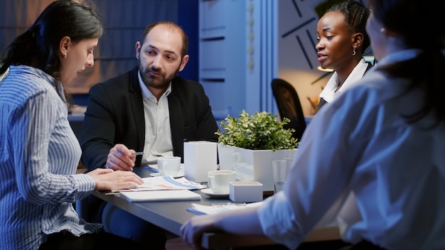 Diverse businesspeople discussing management company solution sitting at conference table