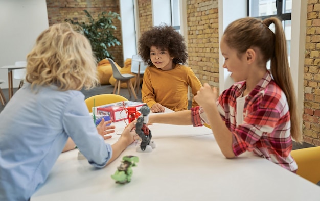 Diverse children examining looking at technical toys on table full of details while having