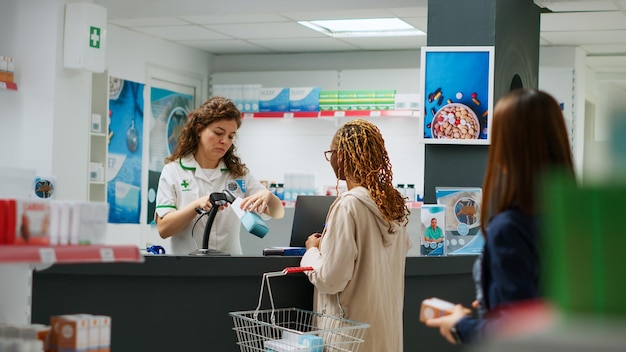 Diverse clients waiting in line at pharmacy to pay medical products with smartwatch, credit card and telephone. Pharmacist selling medicaments and supplements at drugstore, pharmaceutics.