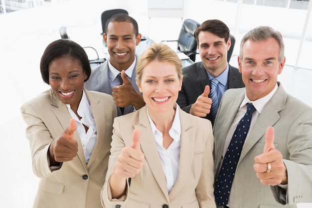 Diverse close business team smiling up at camera giving thumbs up