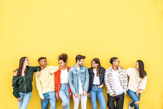 Foto comunità eterogenea di giovani che sorridono insieme su uno sfondo di muro giallo