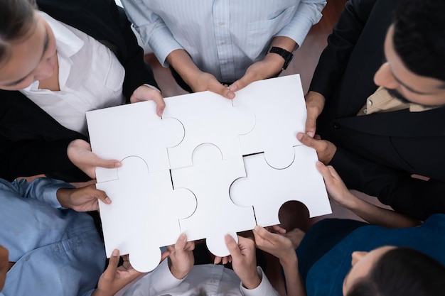 다양한 기업 임원들이 퍼즐 조각을 연결하여 사무실에서 협력하여 파트너십과 팀워크를 표현합니다. 직소 퍼즐 Concord를 병합하여 비즈니스 개념의 단결과 시너지 효과를 나타냅니다.