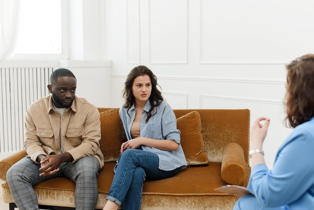 Diverse couple talking to psychologist woman about relationship problems Marital Therapy Family Reconciliation