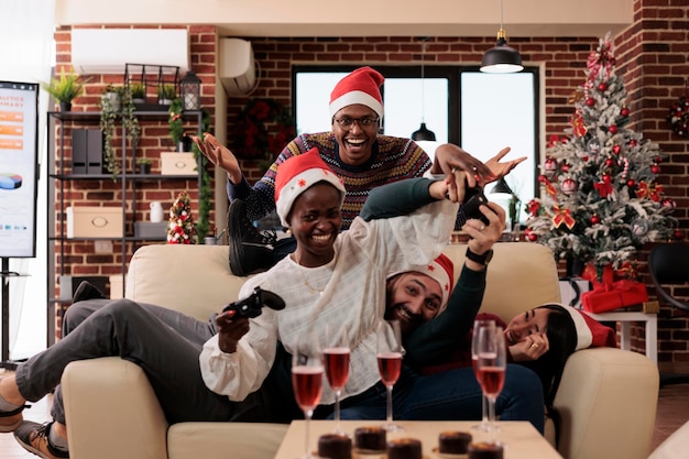 Diversi colleghi che si divertono con i videogiochi giocano il giorno di natale in occasione di una festa in ufficio, celebrando la vigilia di natale con gare di gioco e alcol. i colleghi si divertono con la console durante le vacanze invernali.