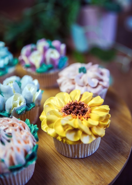 Diverse cupcakes versierd met kleurrijke bloemensuikerglazuur op houten tafel bloemenboeket bruidstaart hallo