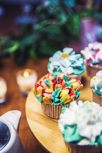 Foto diverse cupcakes versierd met kleurrijke bloemensuikerglazuur op houten tafel bloemenboeket bruidstaart hallo