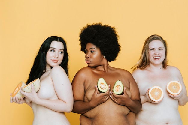 diverse curvy nude women holding fruits over their breasts