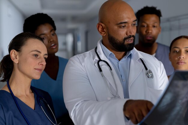 Photo diverse doctors holding x-ray scans and discussing work in corridor at hospital