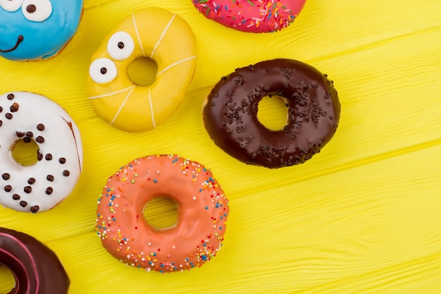 Diverse donuts op gele houten achtergrond. Zoete smakelijke donuts op kleur achtergrond.