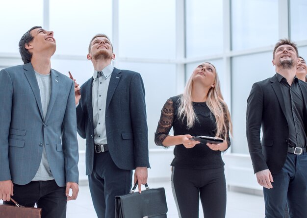 Diverse employees standing in the office and looking somewhere up