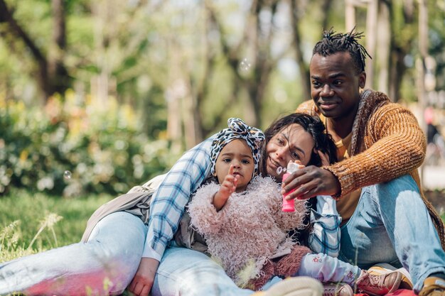 Diverse family blowing soap bubbles in park