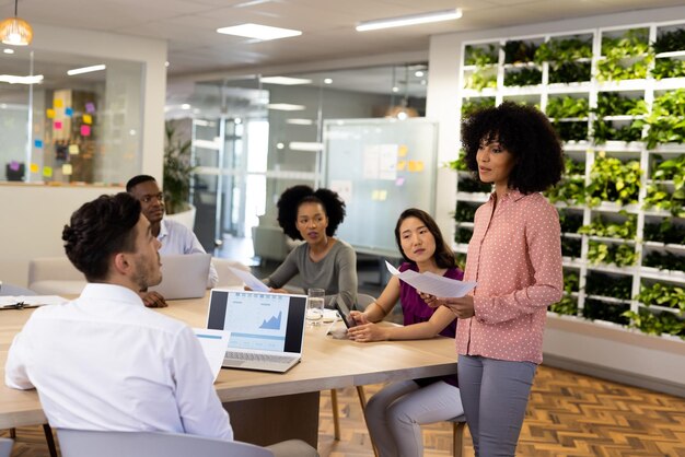 Photo diverse female and male businesspeople with laptops sitting at desk and talking. business, corporation, working in office and cooperation concept.