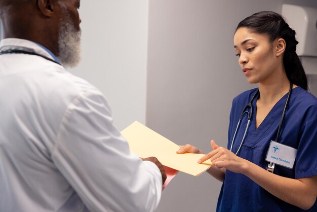 Photo diverse female and senior male doctor looking at file and talking in hospital, copy space. hospital, medical and healthcare services.