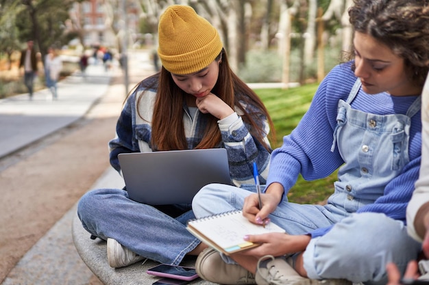 Diverse friends collaborate on campus project sharing laptops and ideas