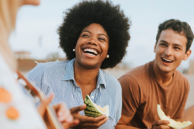 Diversi amici che godono il loro picnic sulla spiaggia