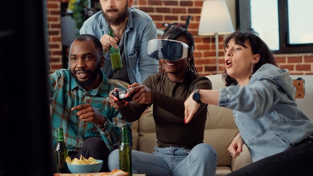 Diverse friends feeling sad about losing video games play with vr glasses and tv console at home gathering. Frustrated people using virtual reality headset to lose challenge. Handheld shot.