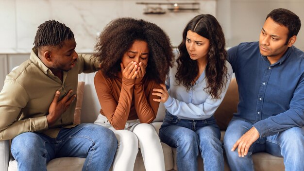 Photo diverse friends providing support to unhappy crying black lady indoor