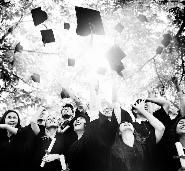 Foto diversi laureati che lanciano cappelli in aria