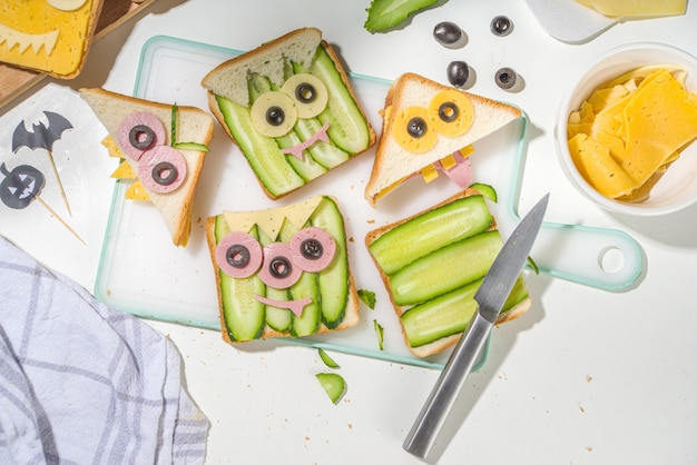 Diverse grappige monster Halloween sandwiches. Creatief ontbijtsnacktoosts koken met kaas, Halloween-kinderfeestvoedsel, moedervrouw handen in bovenaanzicht van de foto